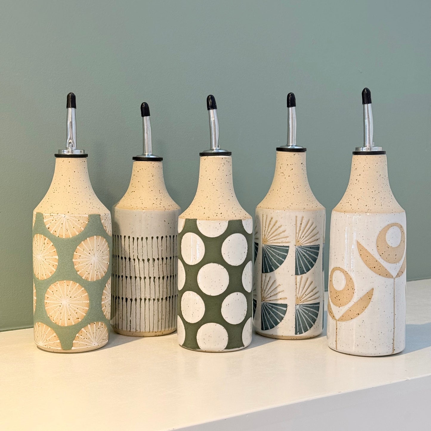 Set of five decorative bottles with unique patterns on a neutral background